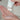 Hand holding a white bottle with a pump, dispensing liquid into another hand against a neutral background.