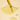 Yellow Botanical Recovery Serum from LOA liquid being dripped onto a beige surface with a droplet forming.